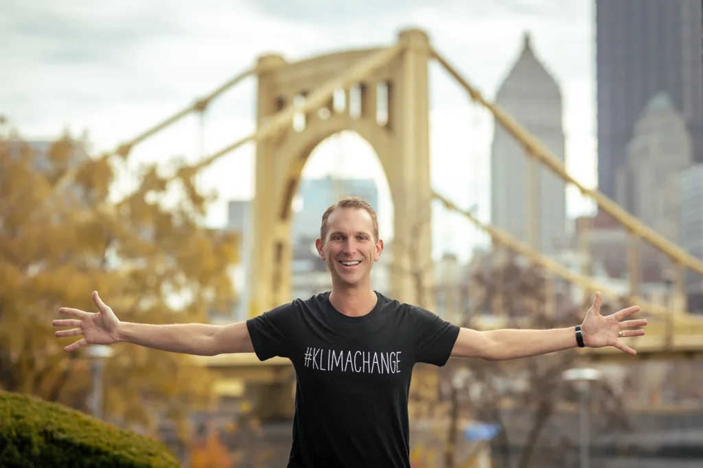 Andrew standing in front of the city of Pittsburgh with his arms spread open